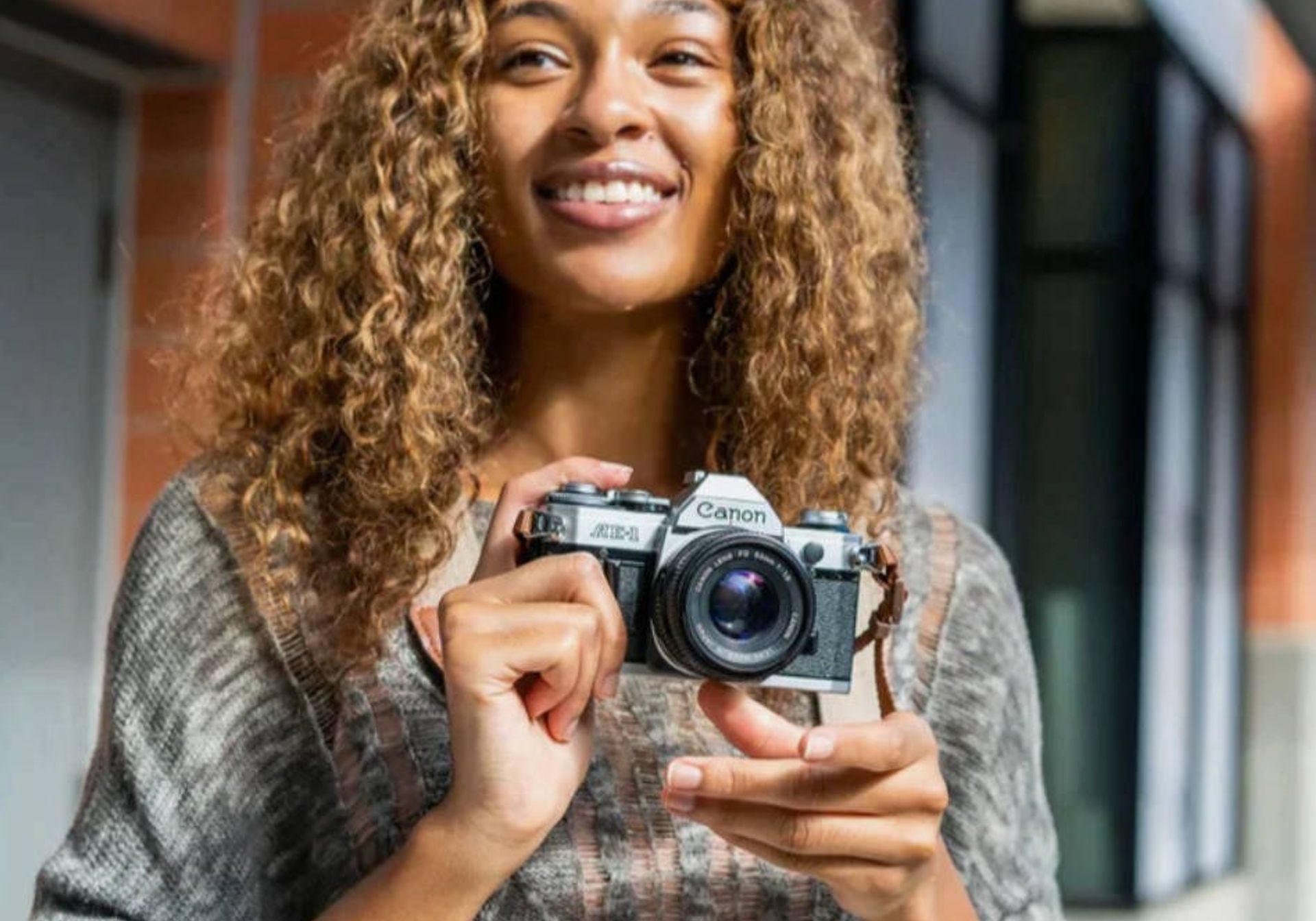 Lady holds the Canon AE-1 camera smiling