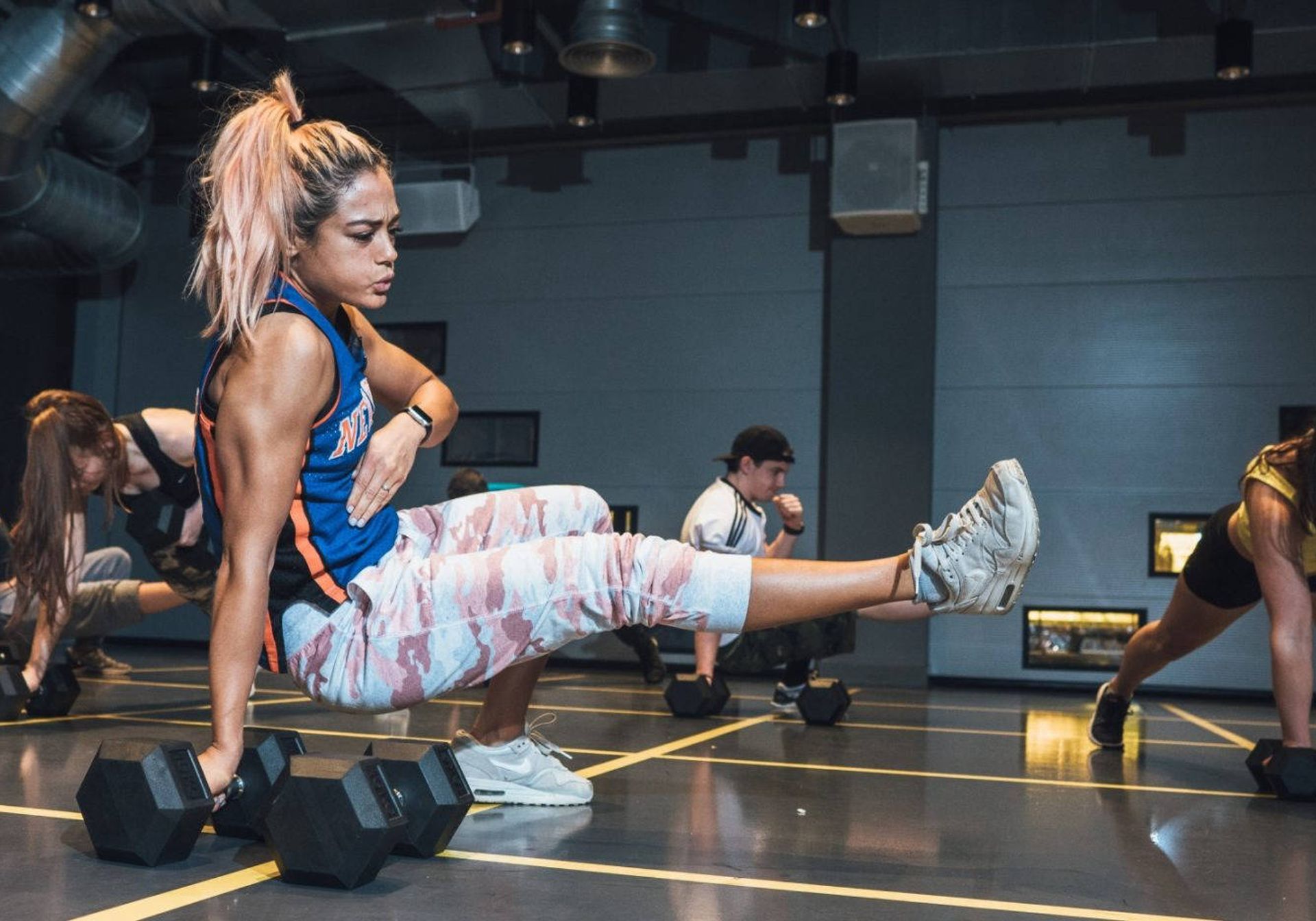 a girl with blonde hair doing a gym move on the floor at gymbox