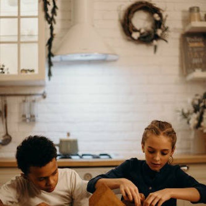 Two children baking a gingerbread house 