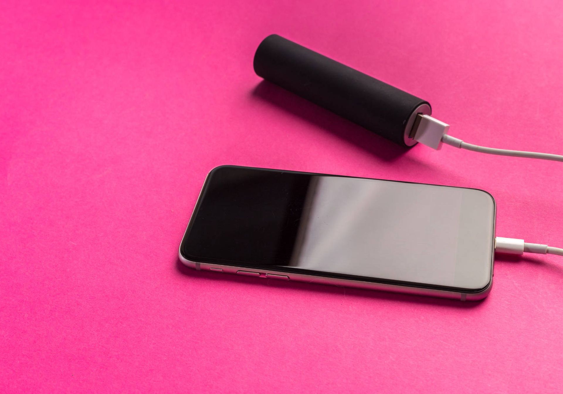 Pink background - Phone plugged into portable charger 
