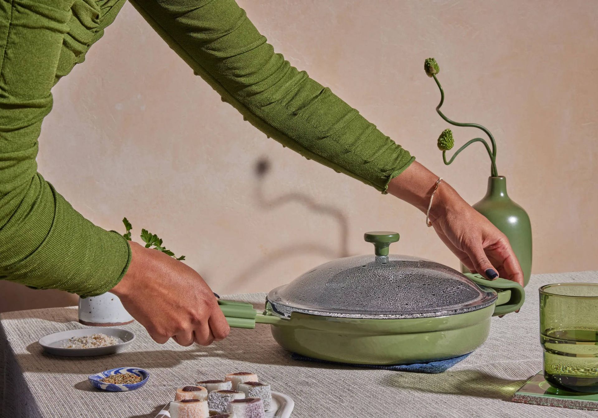 woman in green shirt putting down a green pan using ourplace hot grips