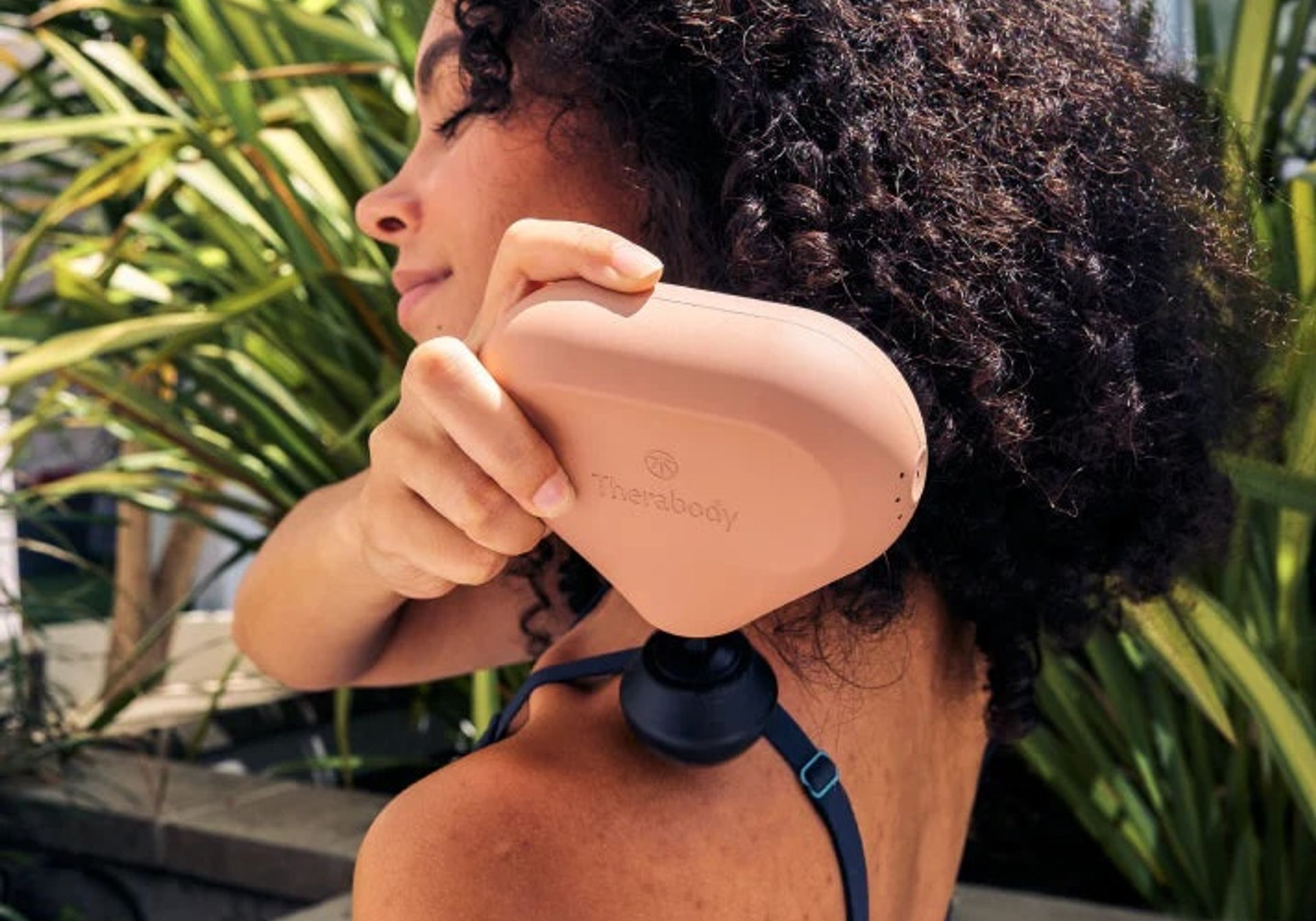 woman using theragun on shoulder