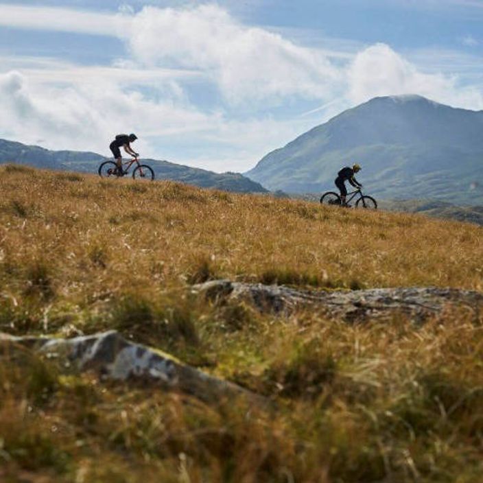 two people mountain biking down a slope in Wales