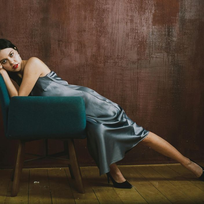a woman with a blue dress lying on a sofa