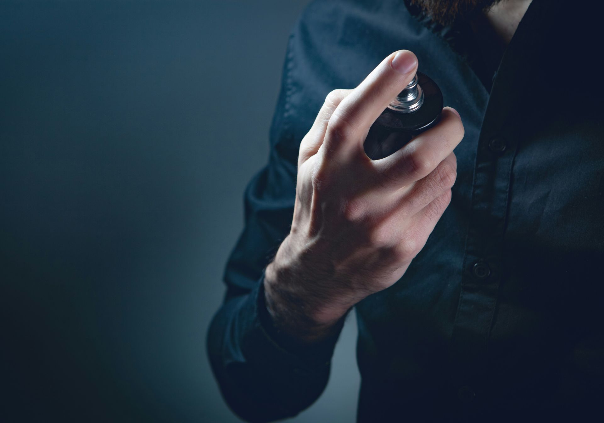 Man spraying perfume on body