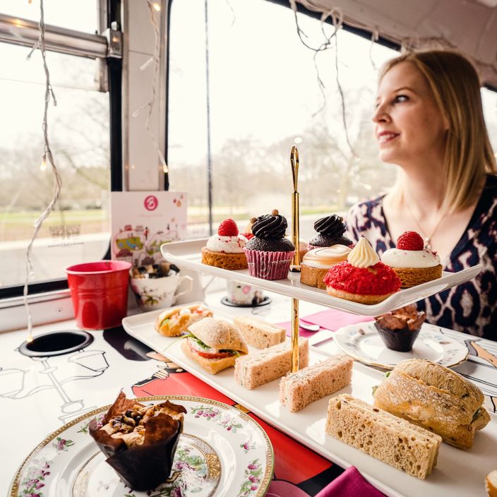 a white woman in a bus with an afternoon tea tray in front of her