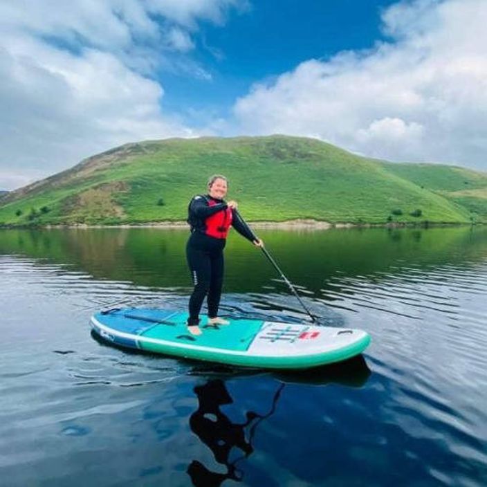 girl standing on paddling board in wales