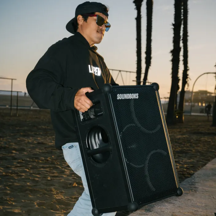 A person holding a Soundboks 4 in their arms
