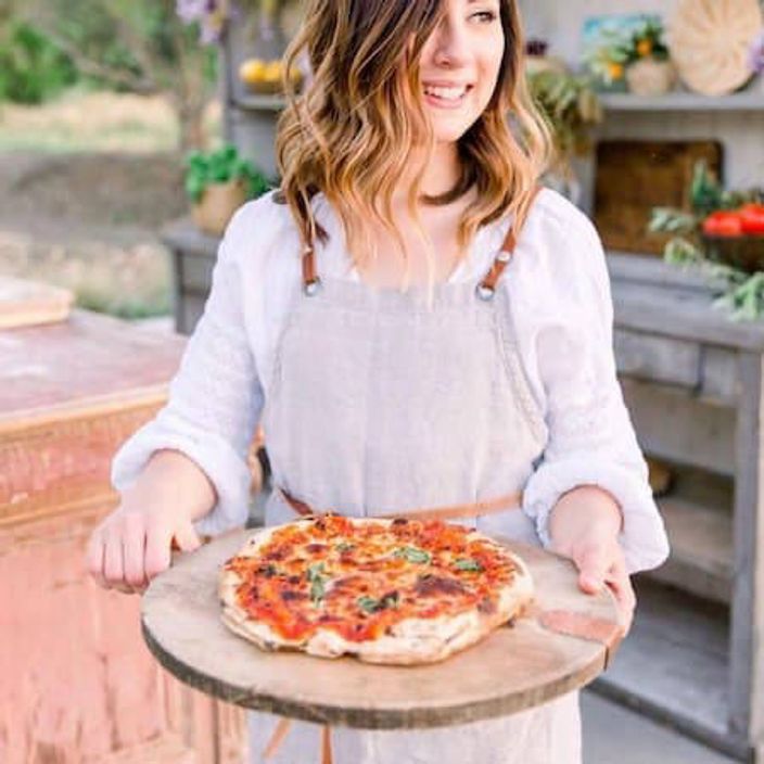 Woman holding pizza on a board