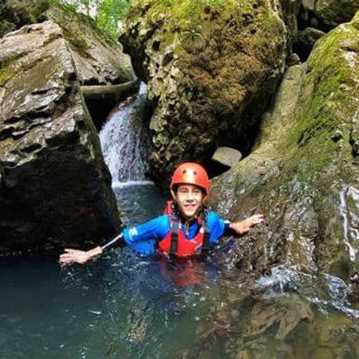 Kid walking through water alongside rocks