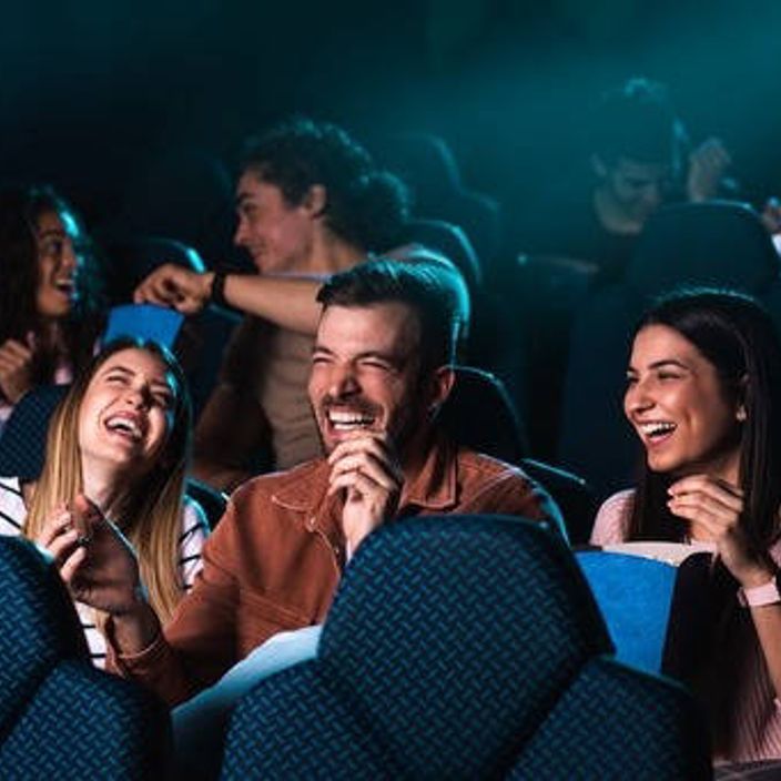 Three watching laughing at a movie in the cinema