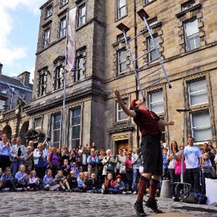 A performer balancing something on his chin with a big crowd watching