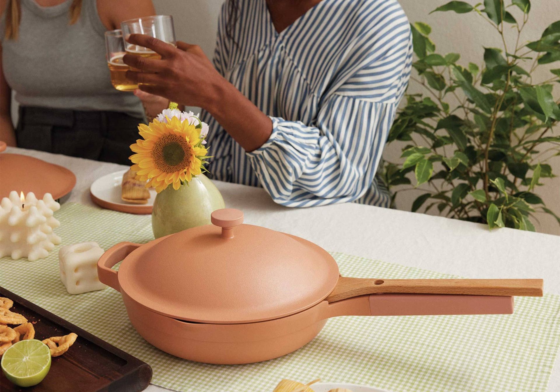 pink ceramc ourplace pan placed next to a bowl of grapes and cleaning gloves