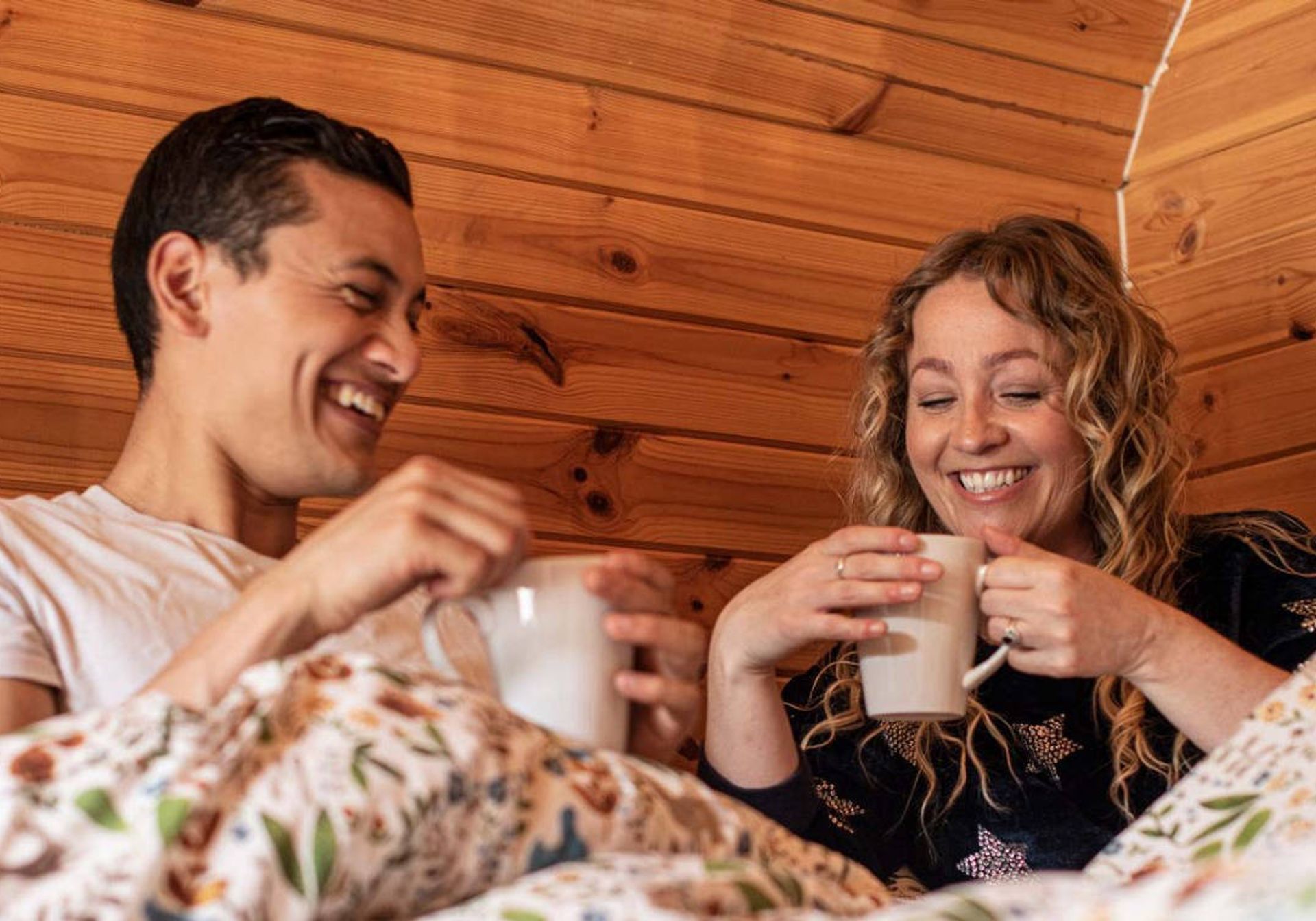 Couple drinking from mugs in cabin