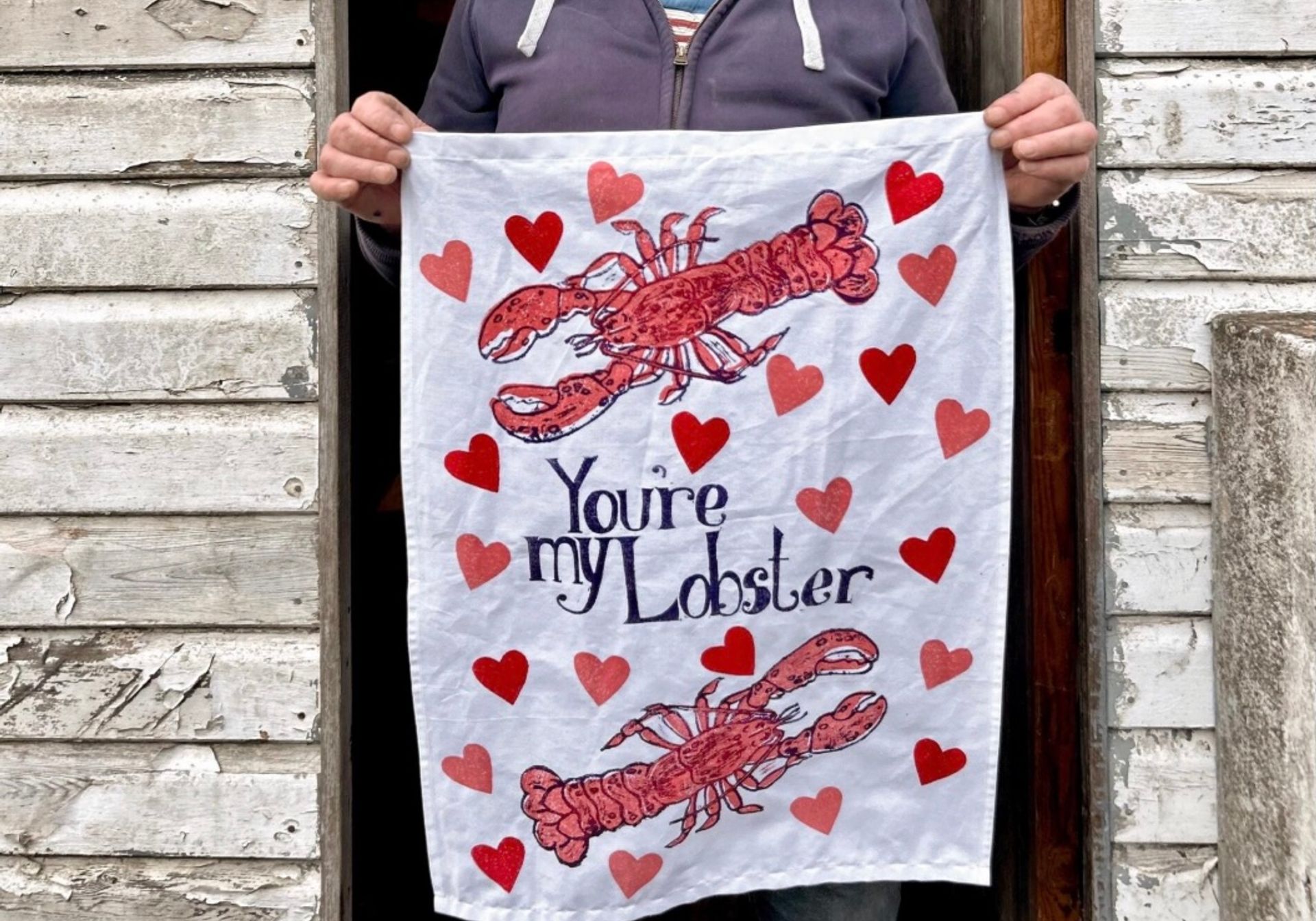 a person holding a You're my lobster tea towel