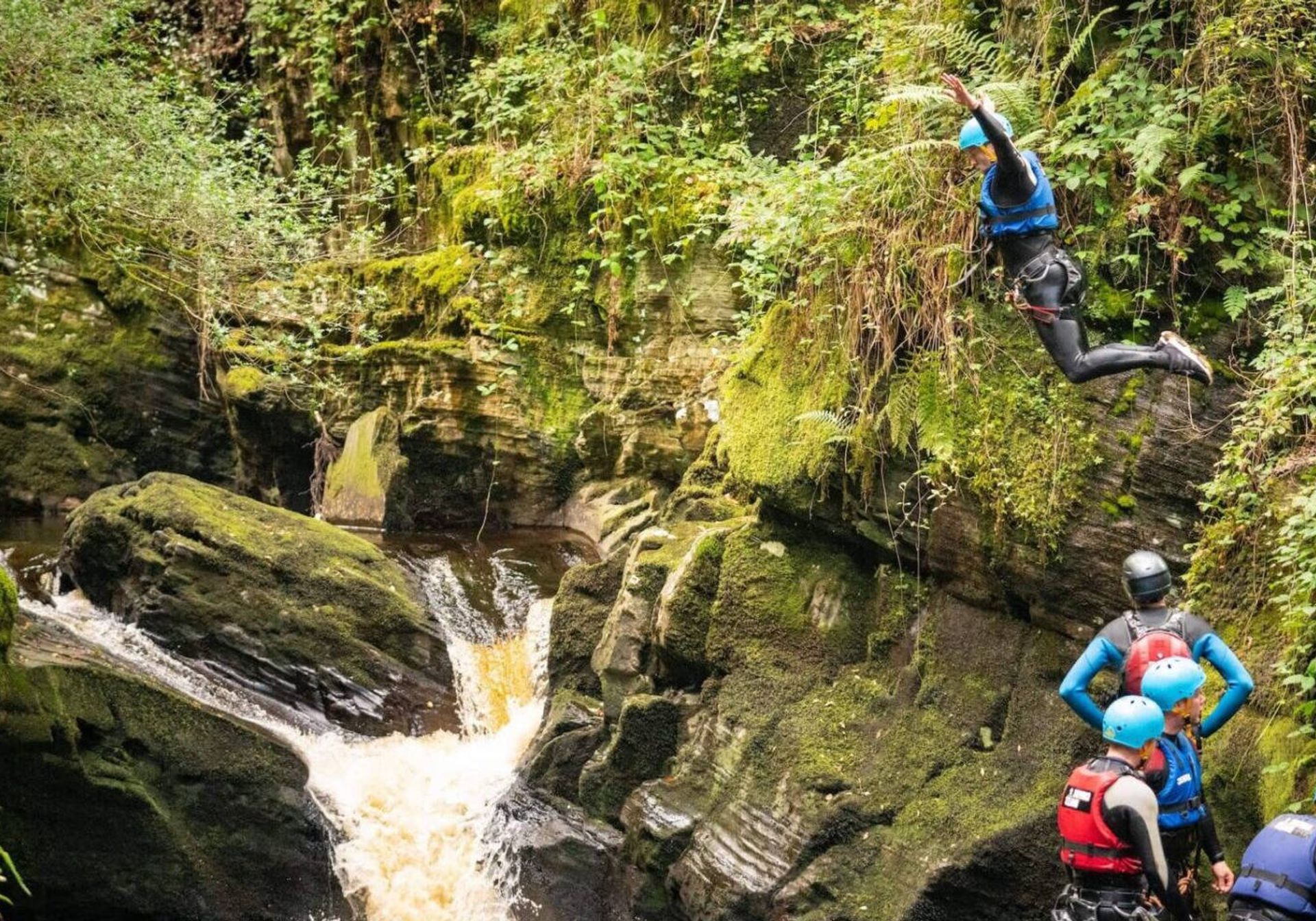 Kid jumping off rock into water in Wales