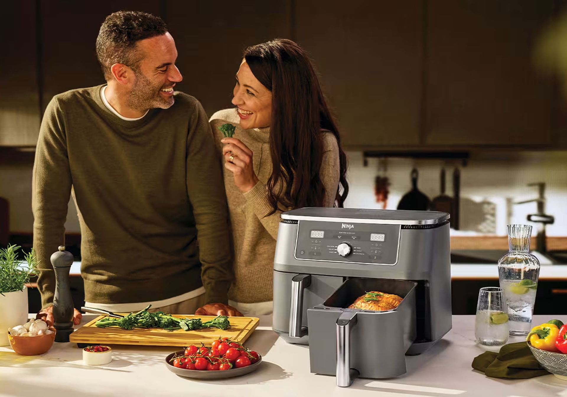 Women taking salmon out of a air fryer and putting it on a plate.