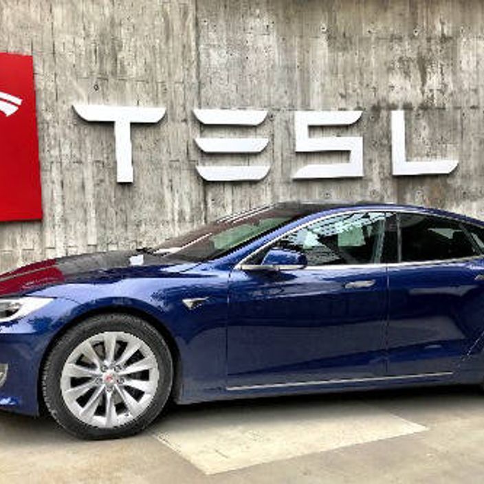 Tesla car displayed in front of a Tesla sign