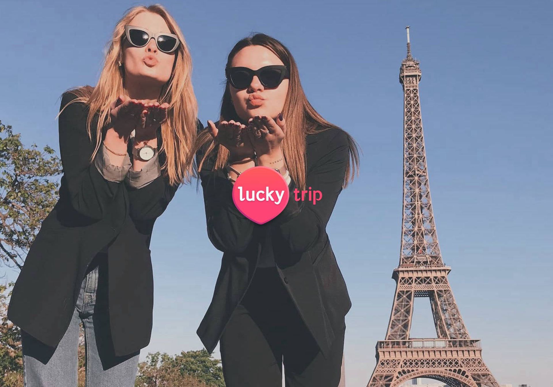 Two women stood in front of Eiffel Tower blowing kisses