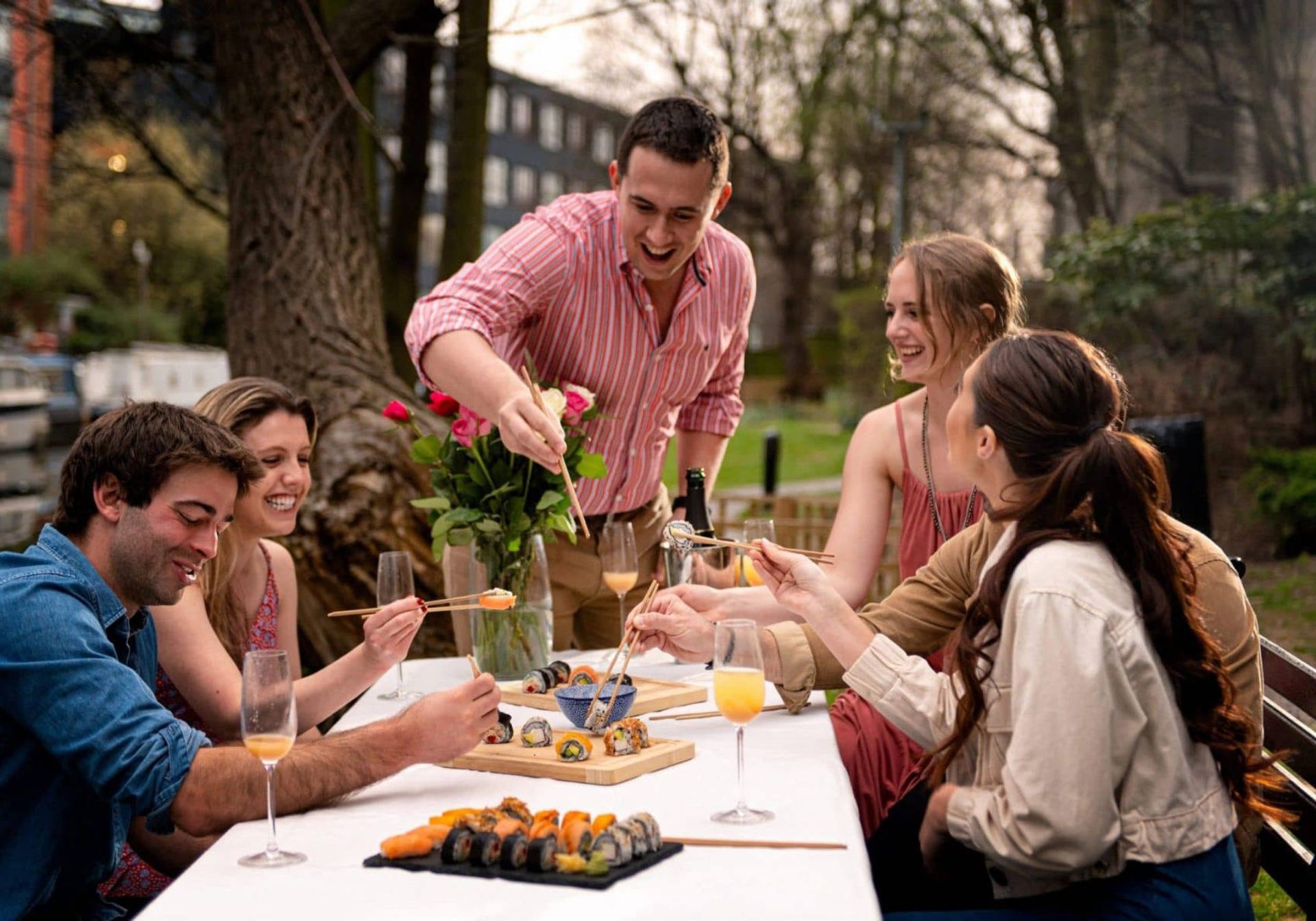 Friends laughing and eating sushi outside