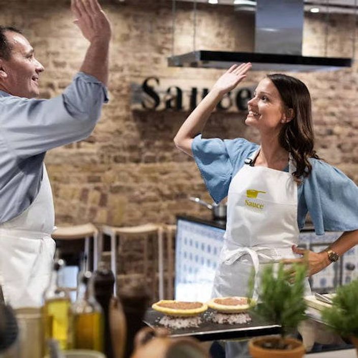 Two cooks giving each other a high five in a cooking class