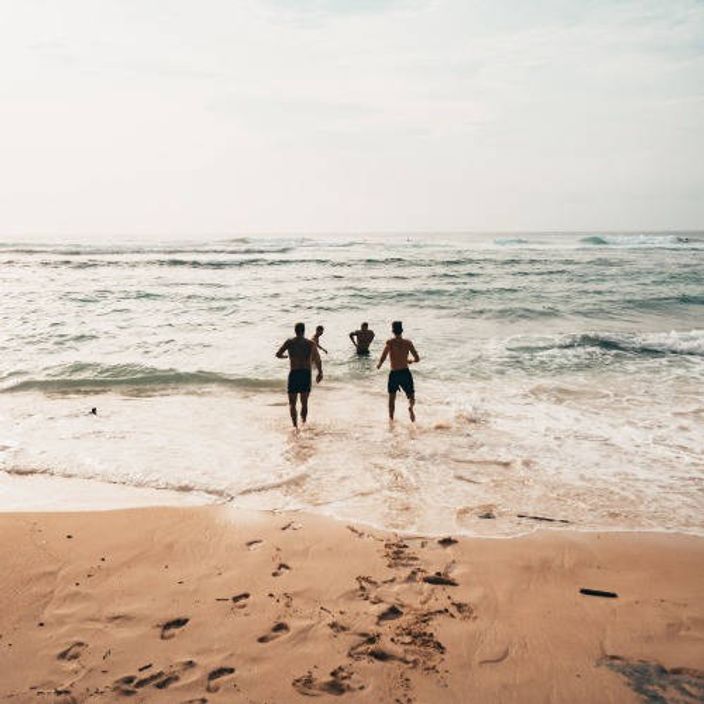 Four people running into the sea