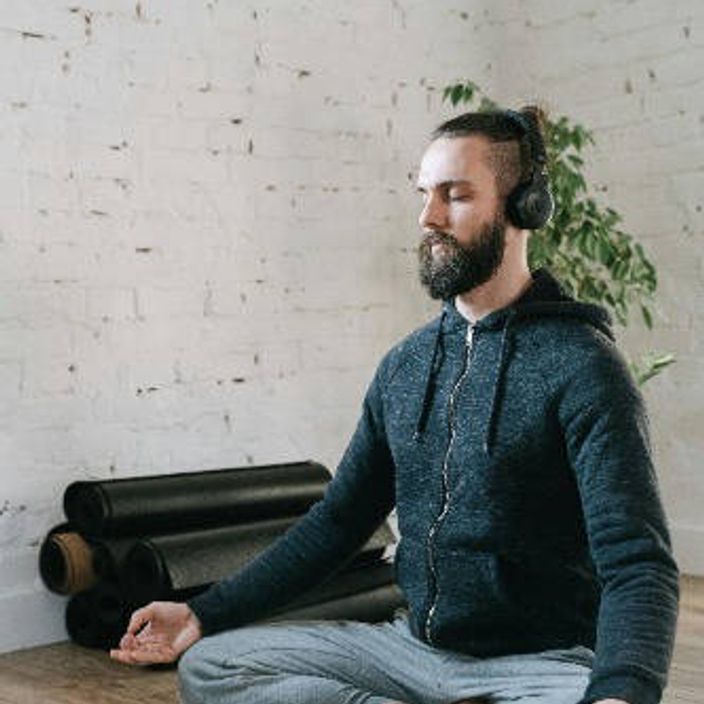 Man sitting cross legged meditating with headphones on