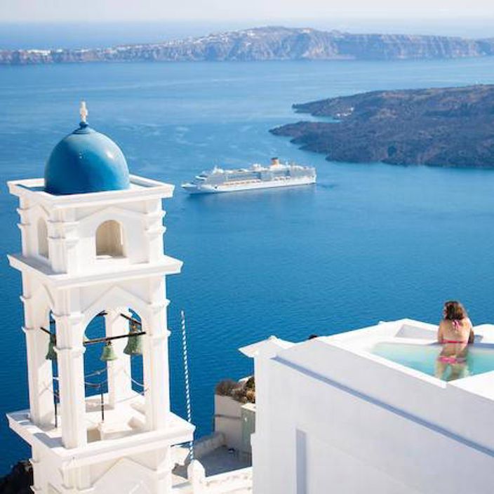 Woman in pool overlooking Santorini