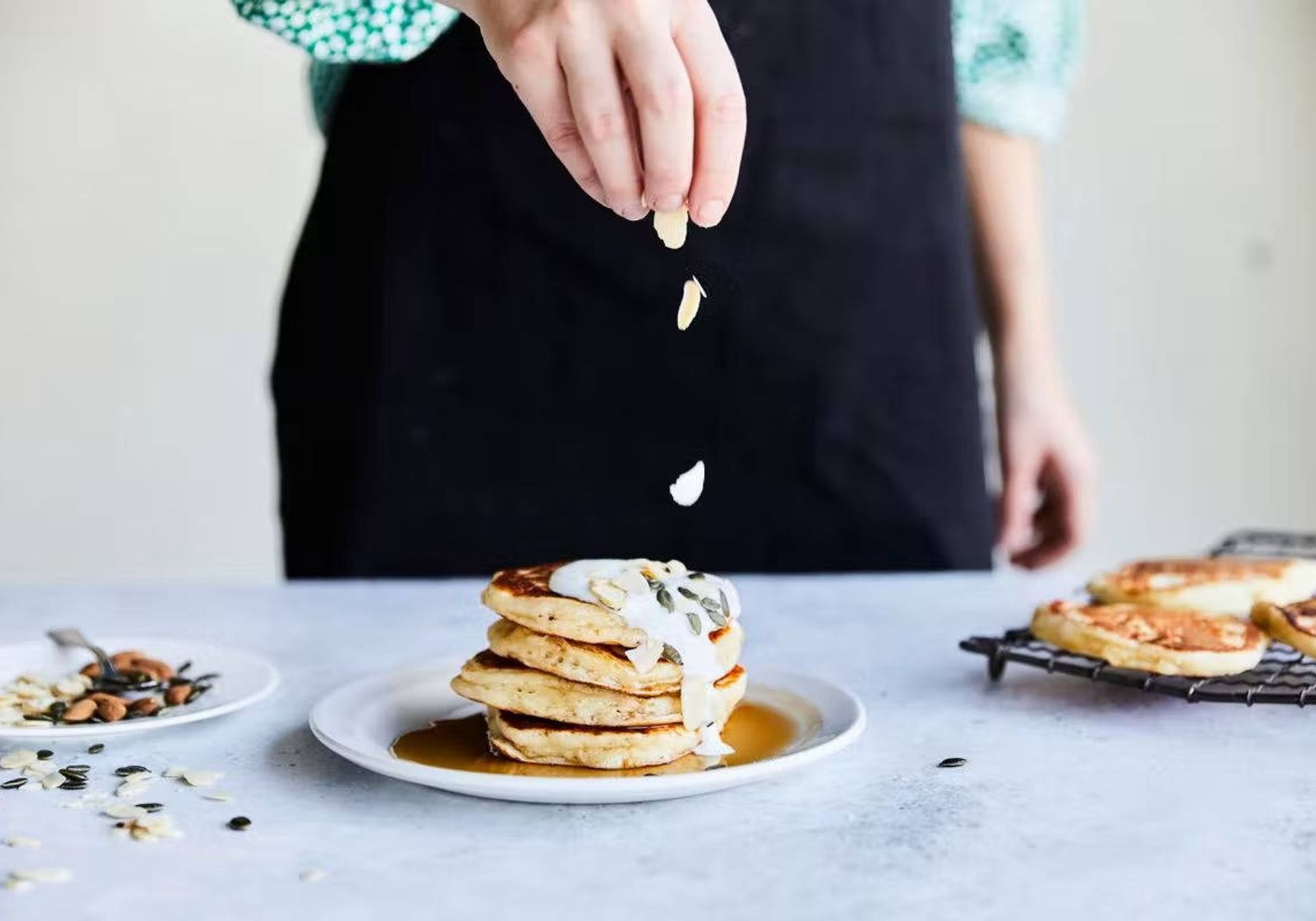Chef sprinkling almonds onto a stack of brunch pancakes