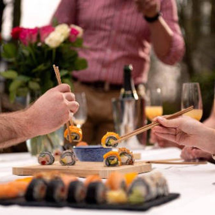 Friends eating Sushi rolls with chopsticks
