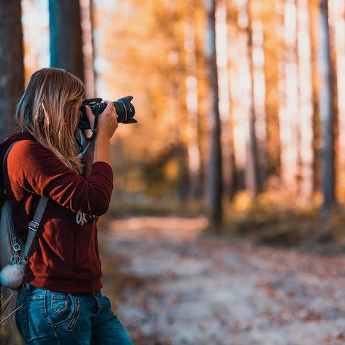 Woman taking a photo in the forest using a DSLR