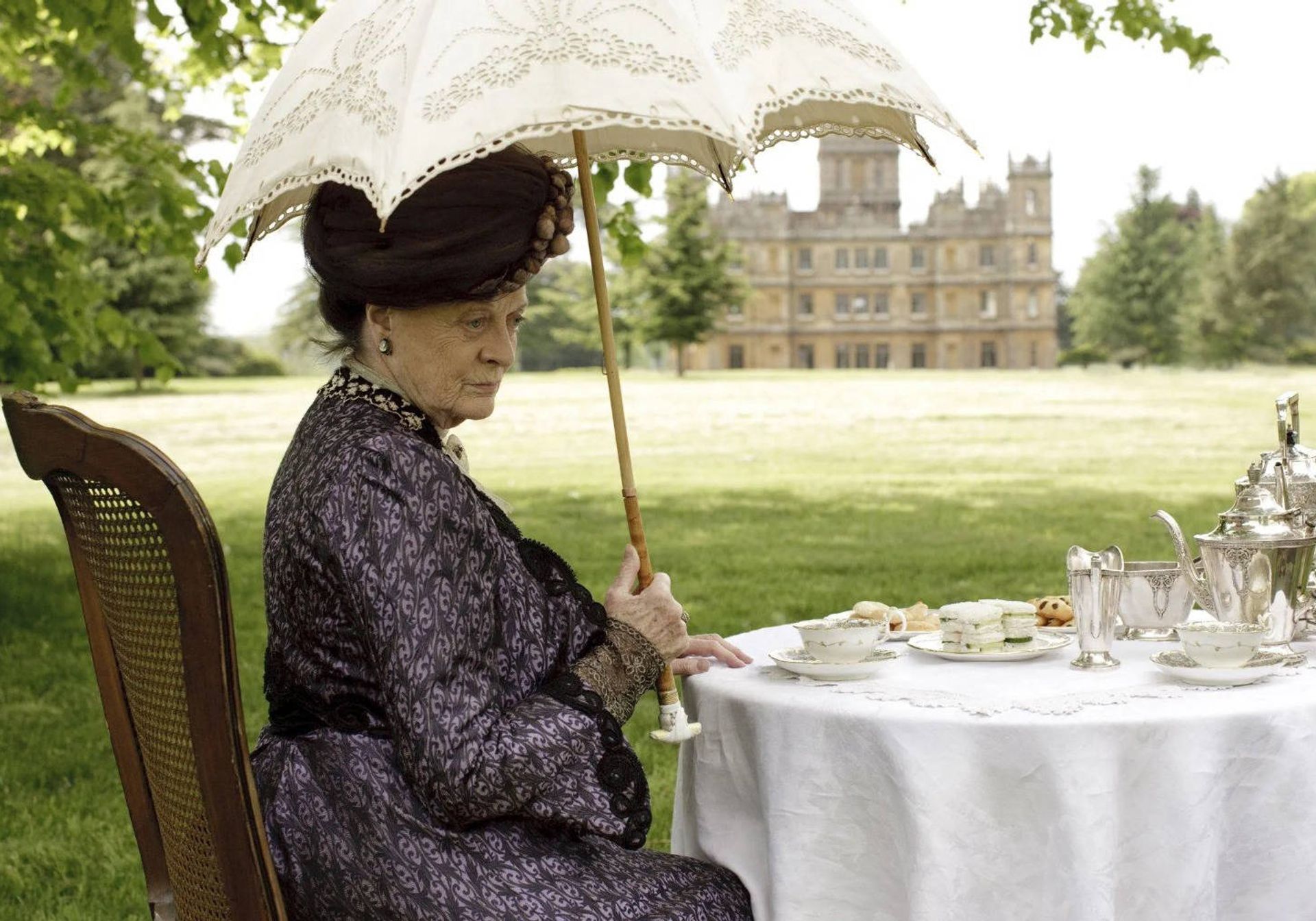 Maggie Smith having afternoon tea in front of Downton Abbey