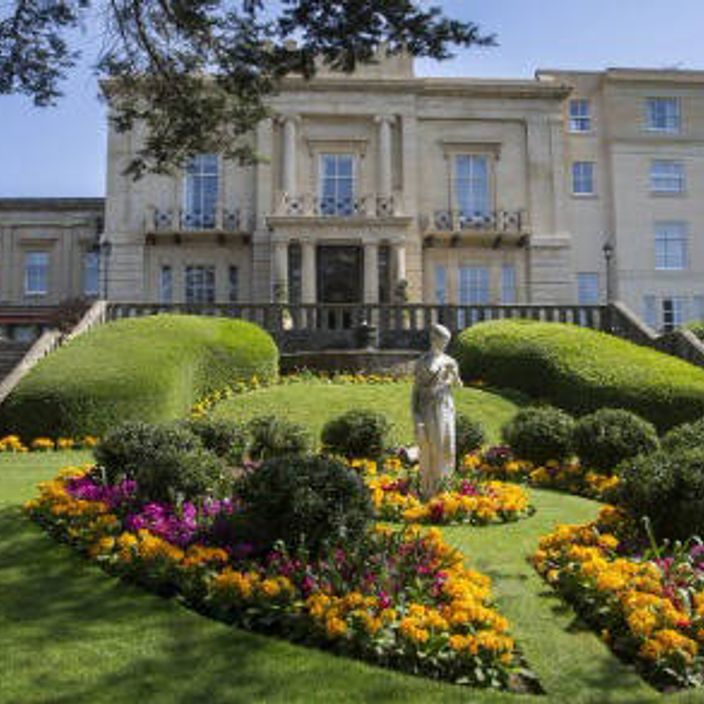 a garden of a macdonald hotel with a statue and flowers in full bloom