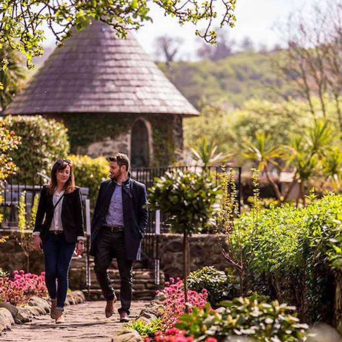 Two people walking through the gardens of Ballygally Castle