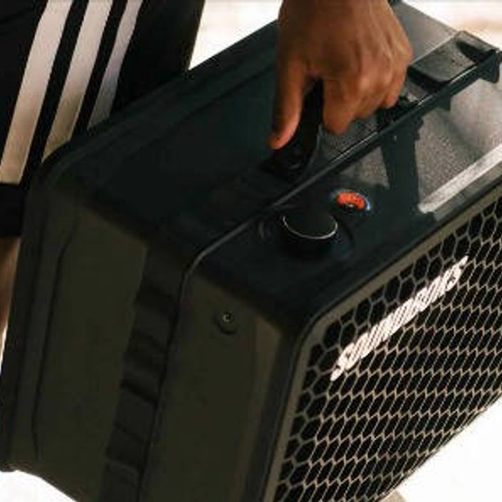 A person carrying Soundboks Go in their hand