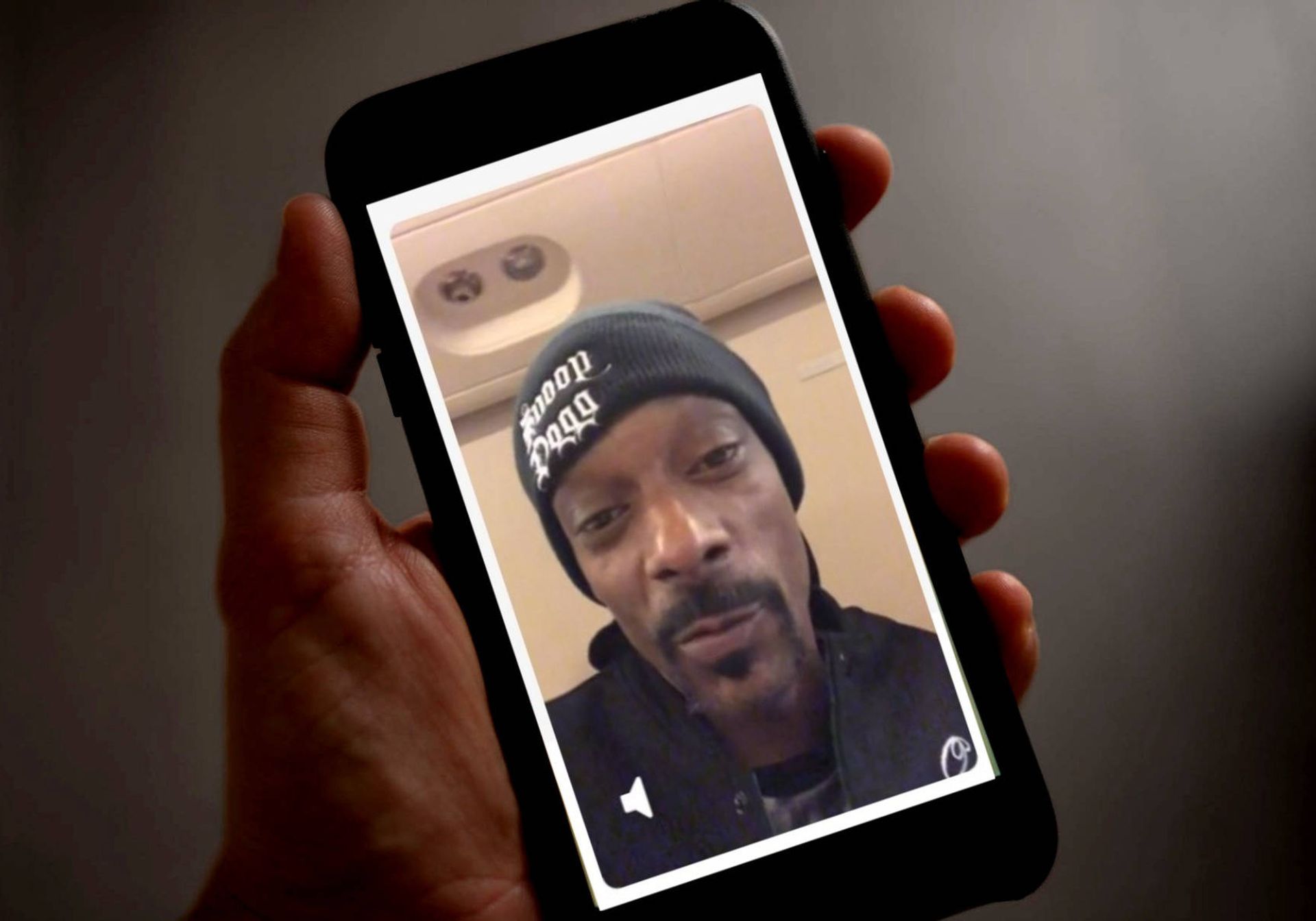 a man holding an iphone that displays a cameo by snoop dogg