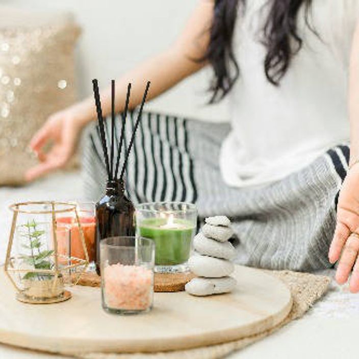 a white woman meditation with candles and scented sticks in front of her