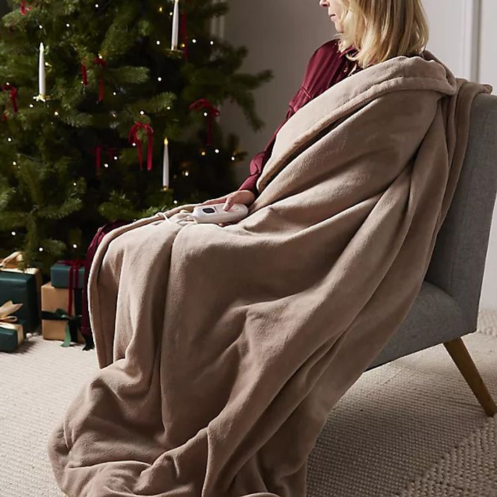 woman with a heated throw sat in a sofa at christmas