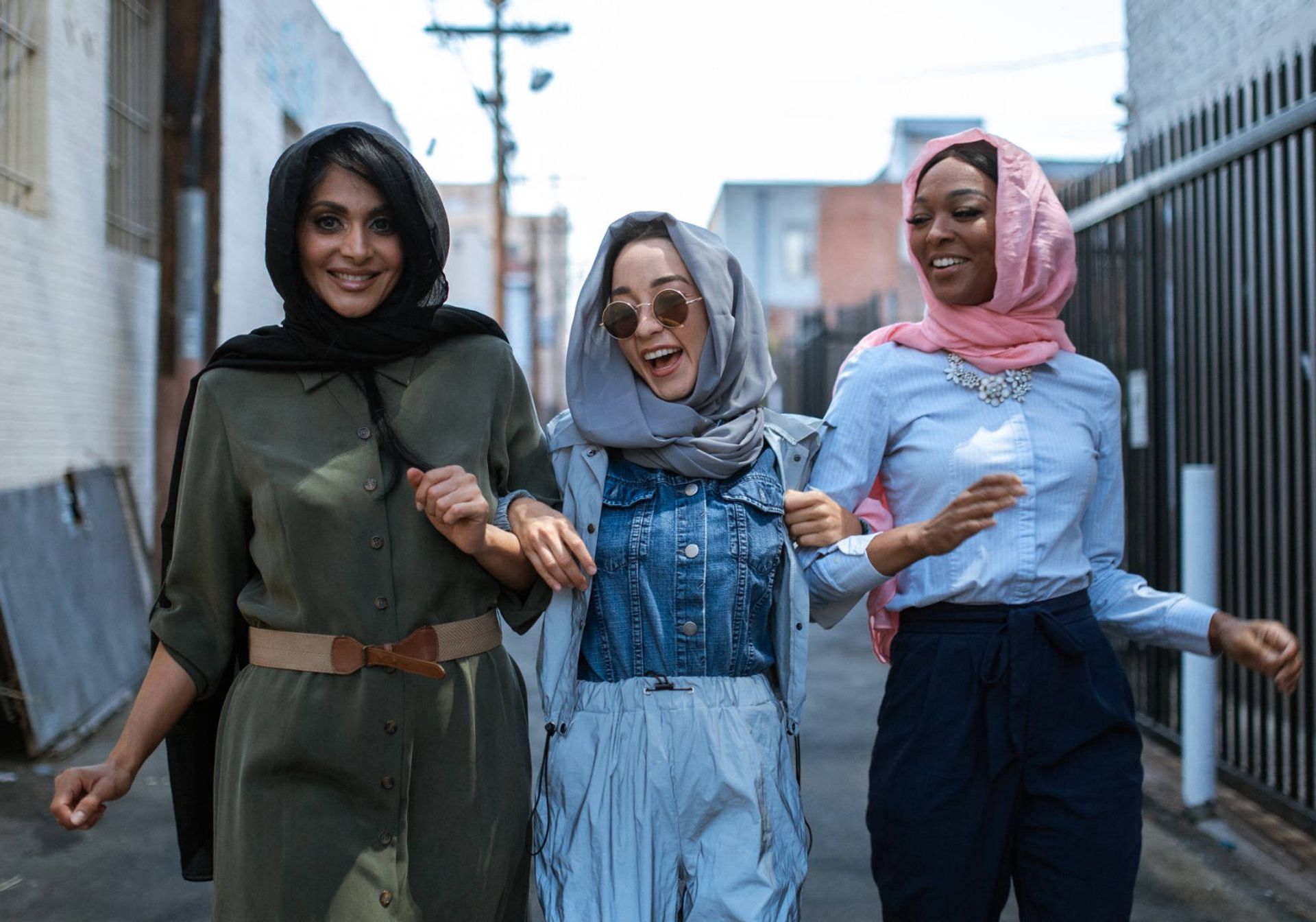 Three women laughing whilst walking down a street