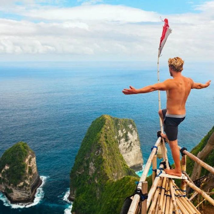a white man spreading his arms in joy and overlooking the sea in Bali