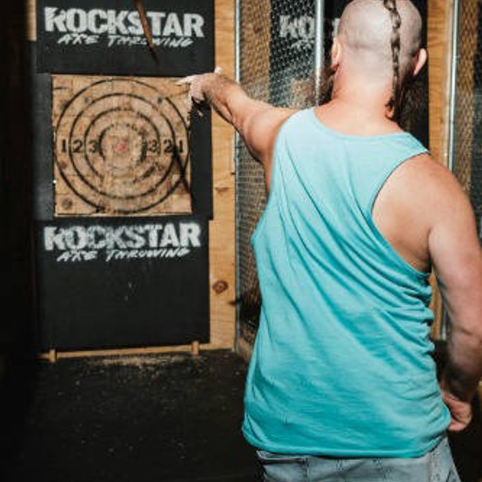 man throwing axe at axe board target