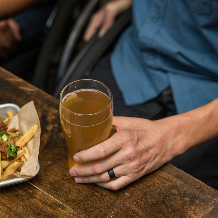 hand grabbing a beer and loaded fries