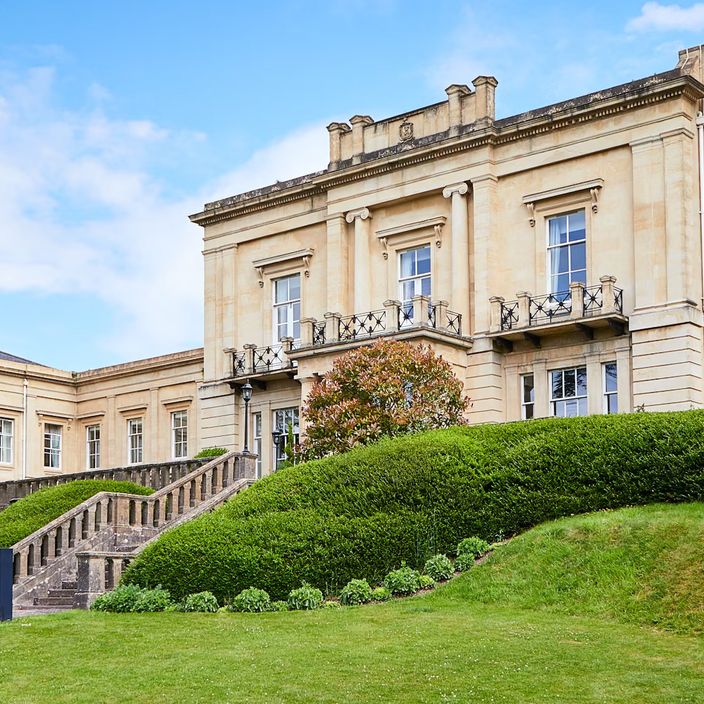 a garden of a macdonald hotel with a statue and flowers in full bloom