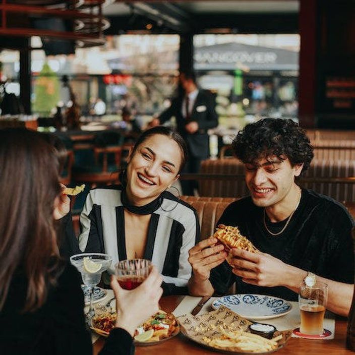 two friends eating and laughing at a restaurant