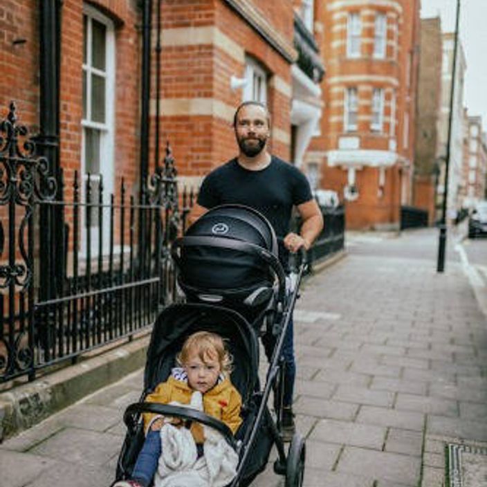 A dad pushing his toddler in a pram