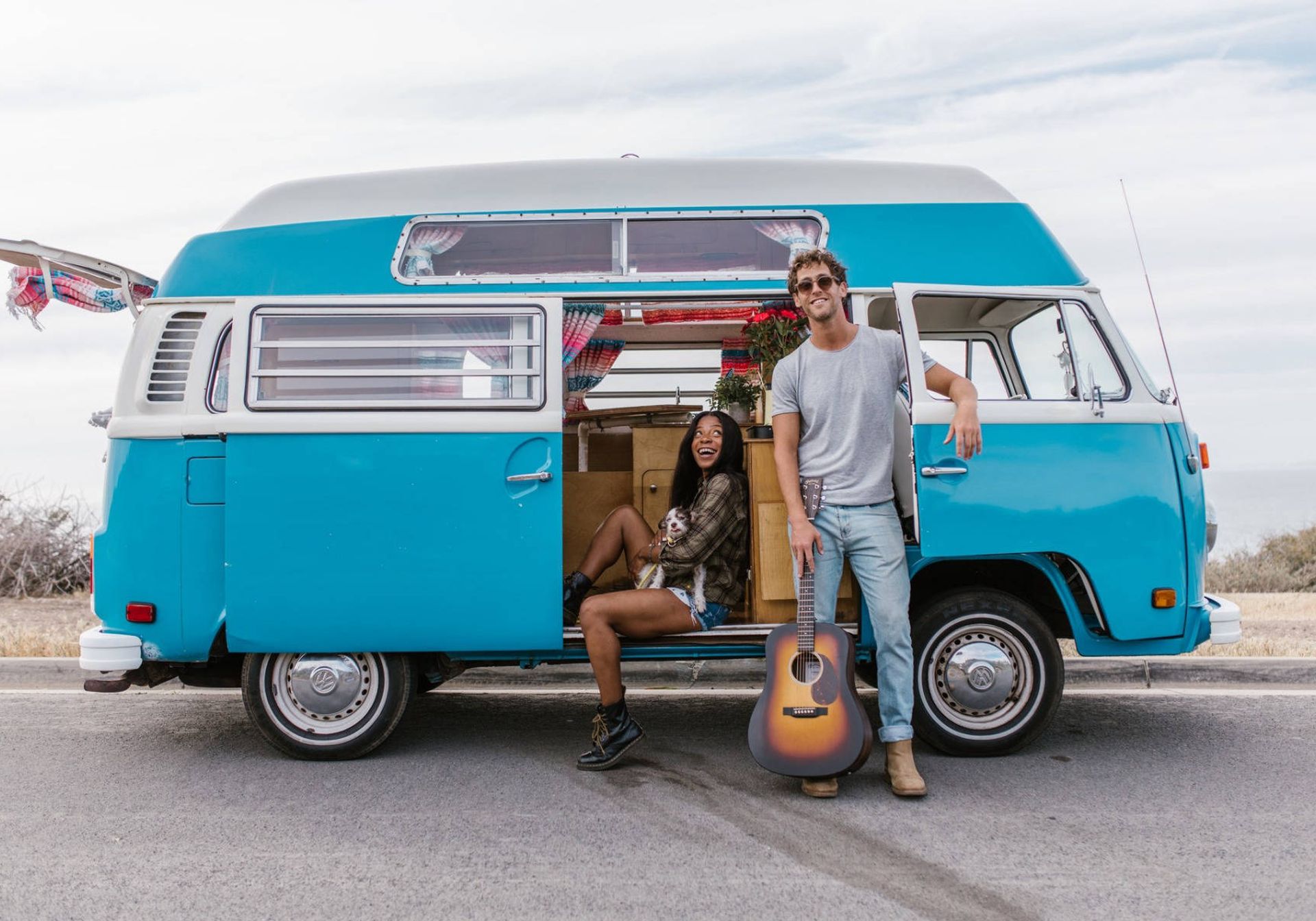 Man and woman with a blue VW Campervan on a roadtrip