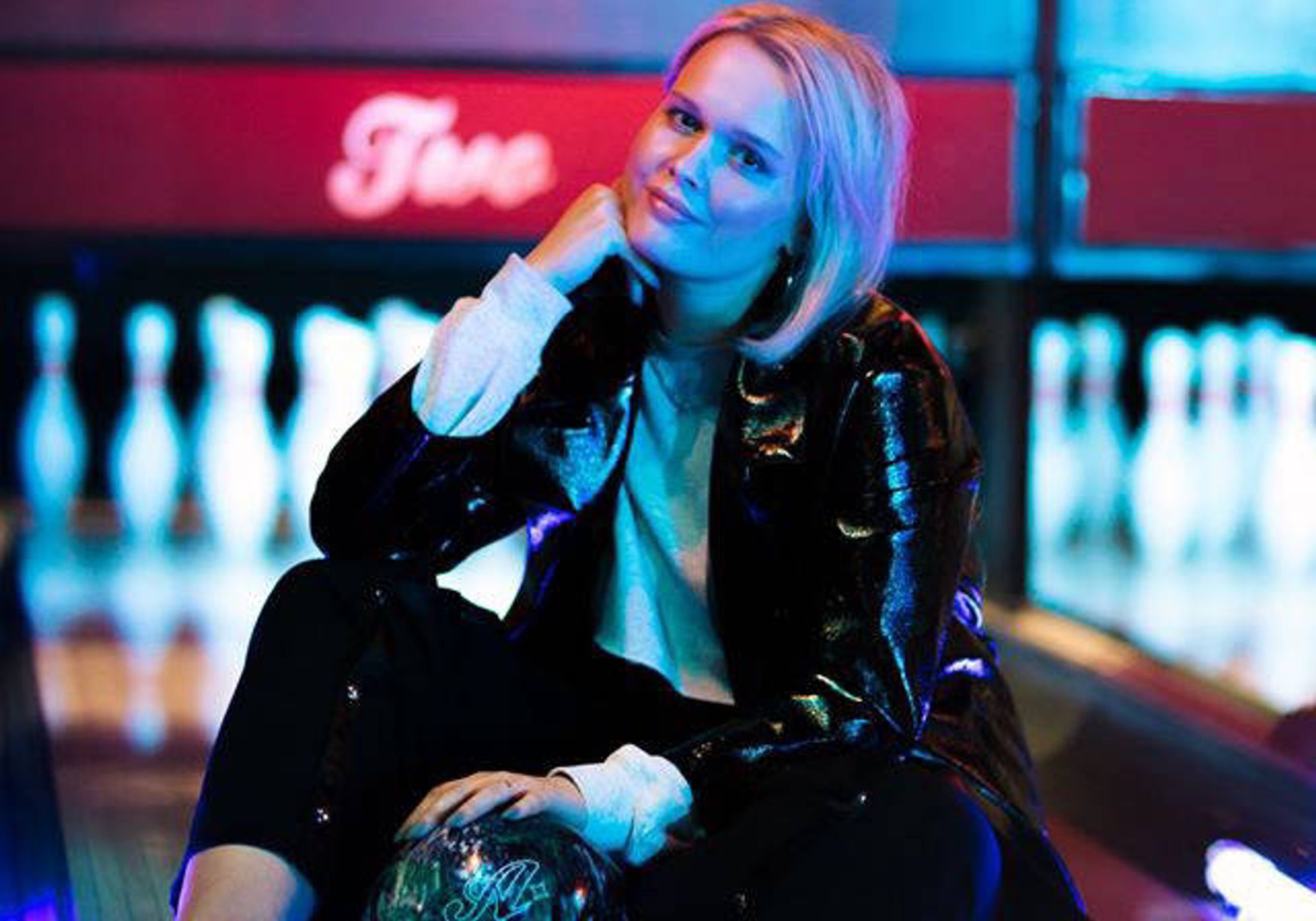 Woman in leather jacket in neon bowling alley