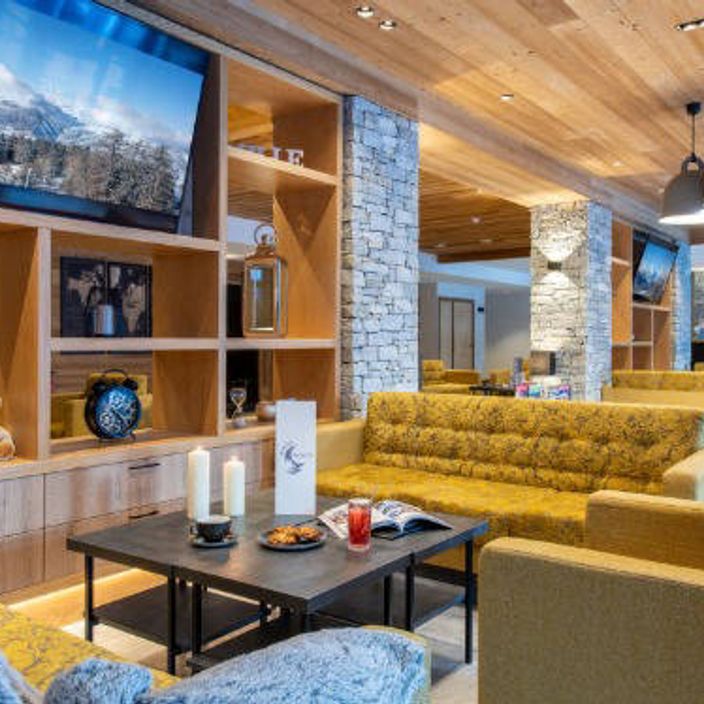 a living room of a skiing chalet, depicting some yellow sofas and a teddybear