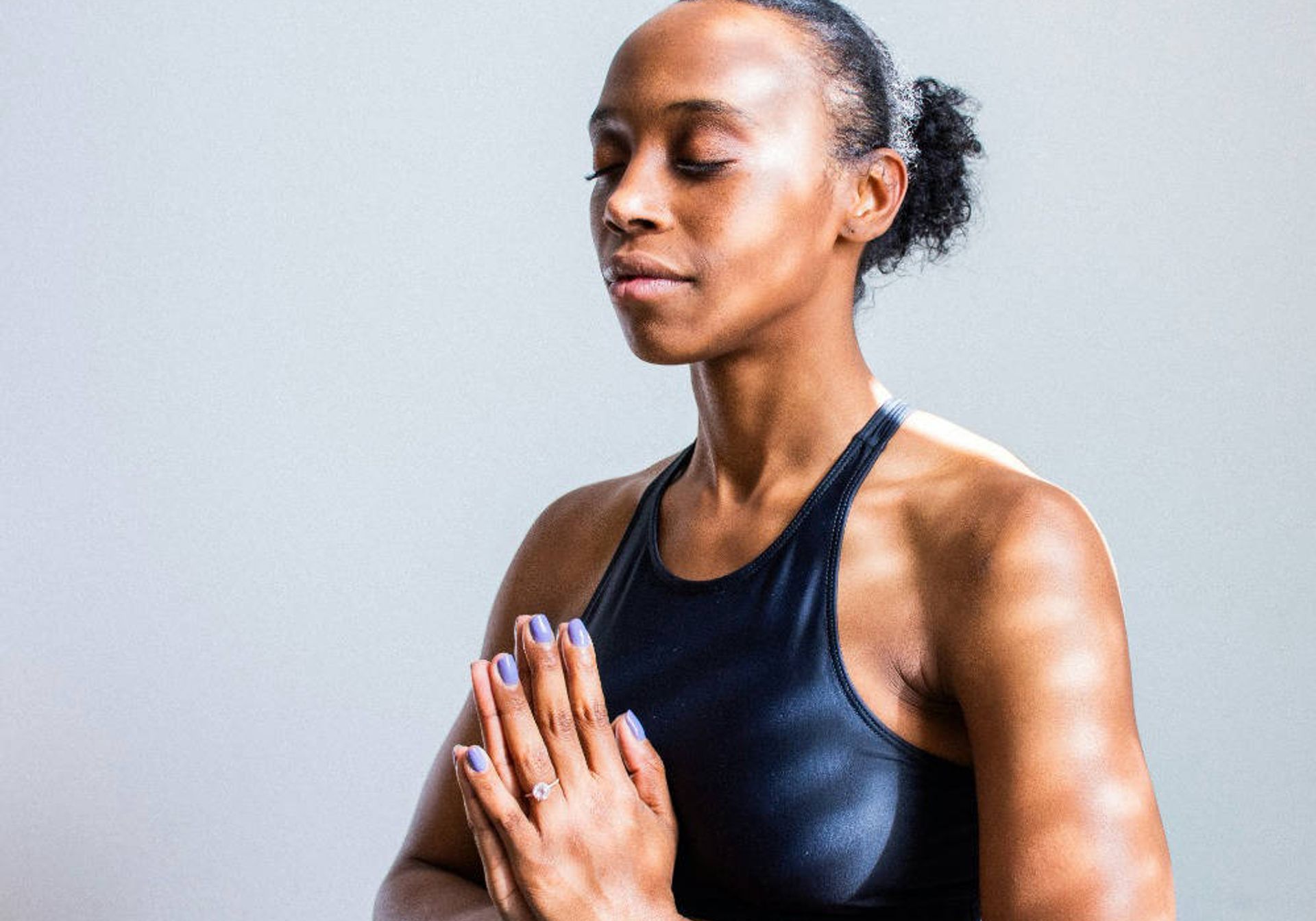 a black woman with her hair in a bun in a zen pose enjoying meditation 