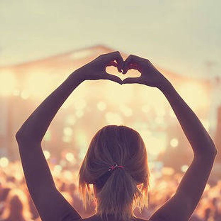 Woman doing a heart with hands at a concert